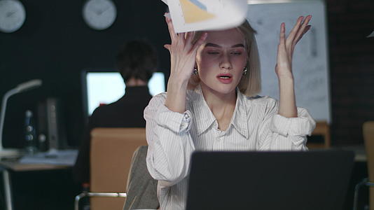 失望的商业女性把文件放在黑暗办公室的笔记本电脑前视频的预览图