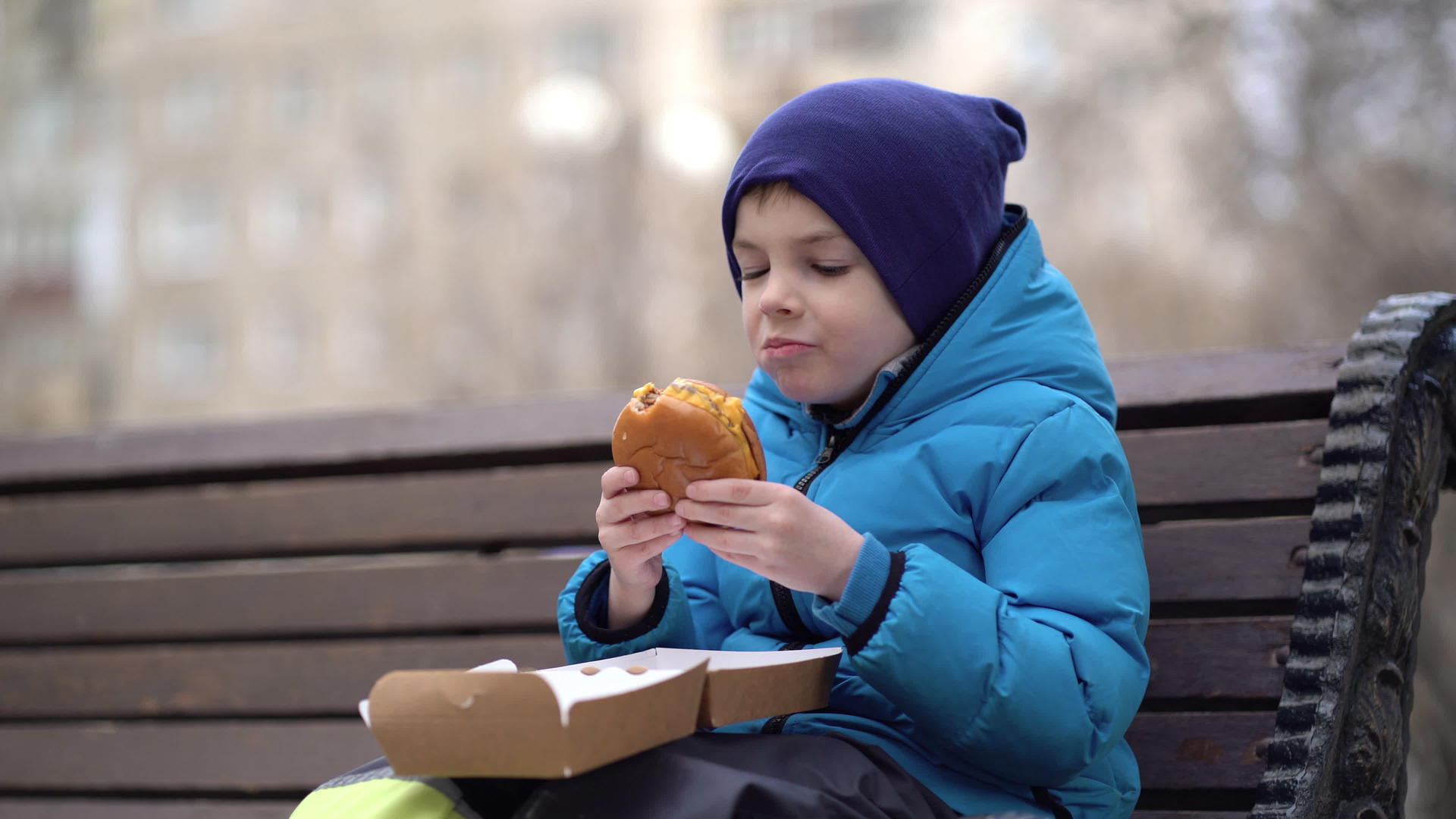 饥饿的孩子在户外吃双层奶酪汉堡视频的预览图