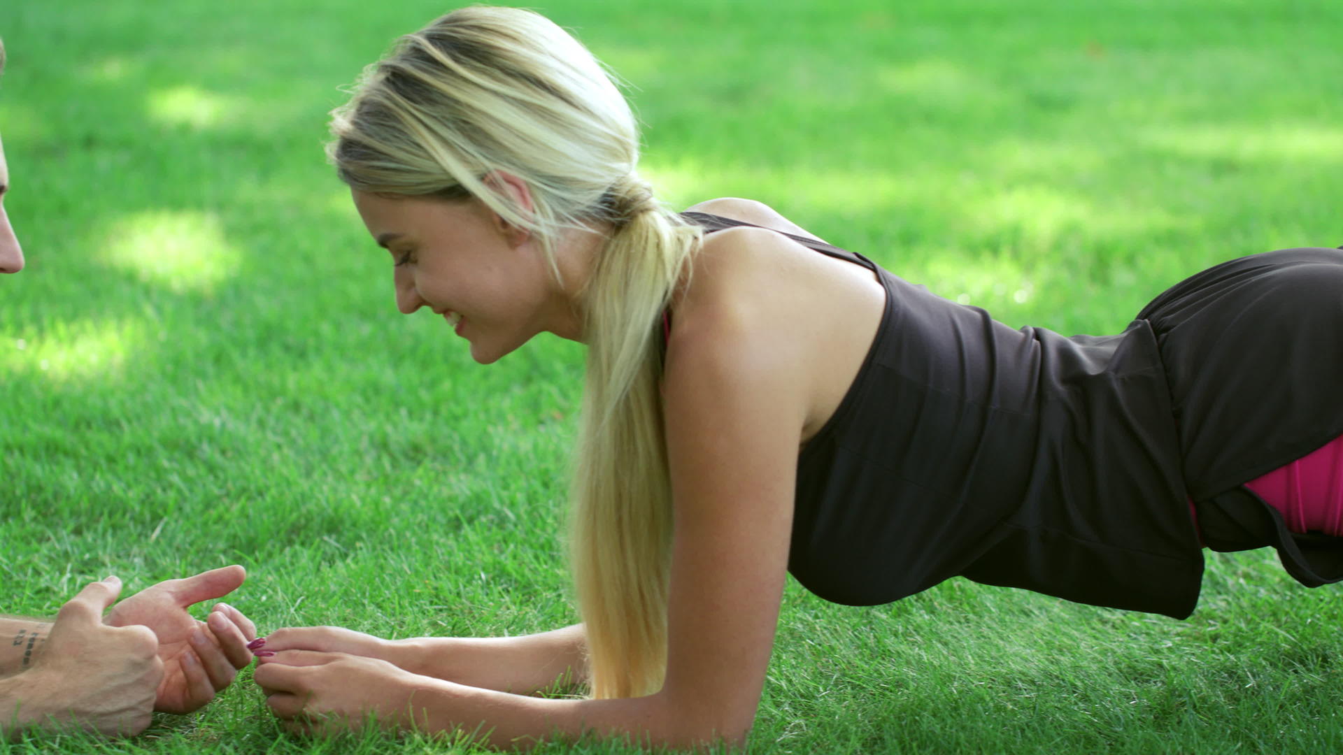 与躺在公园草地上的教练一起进行健身妇女训练木板练习视频的预览图
