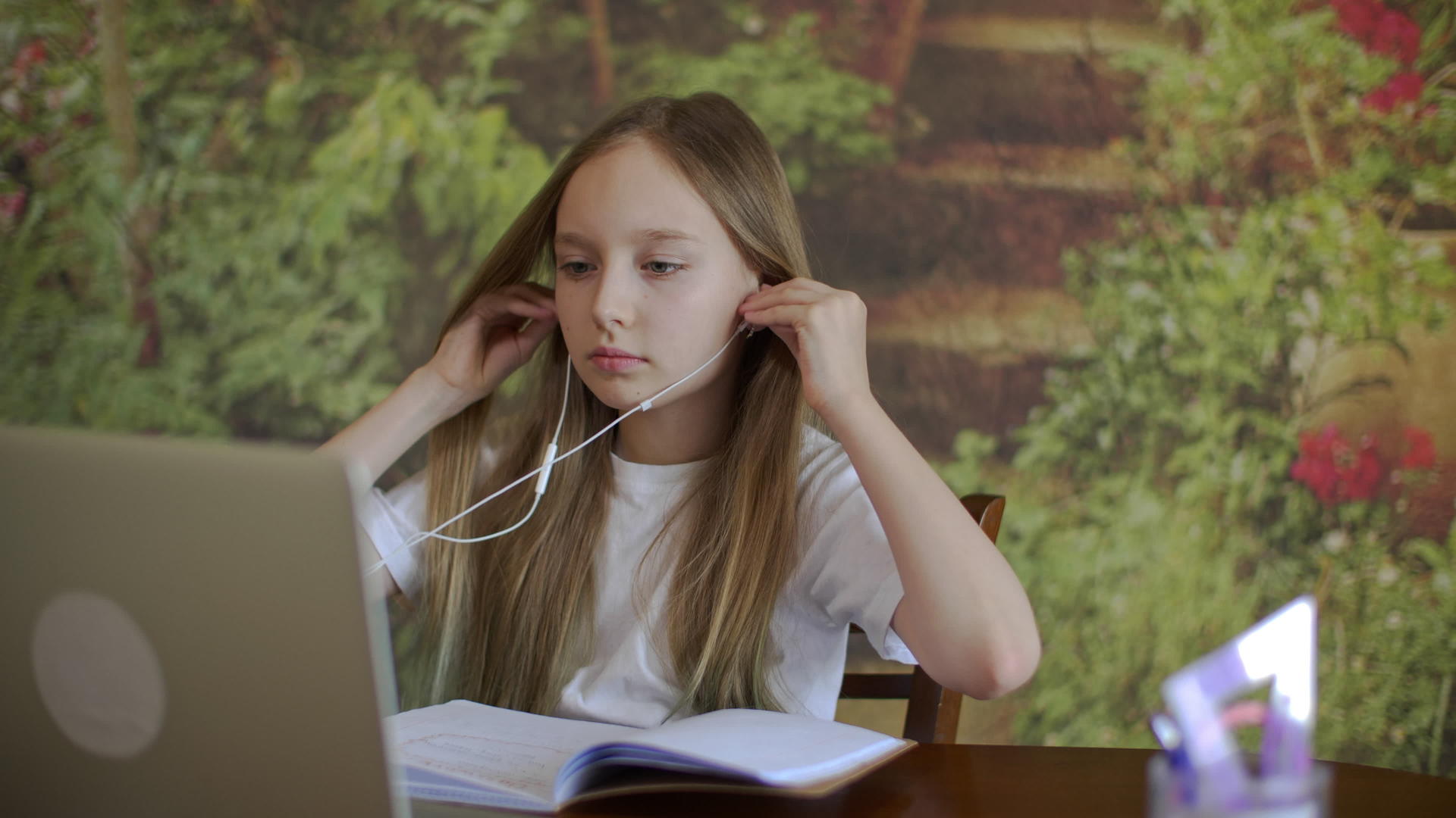 一个女孩戴着耳机看笔记本电脑视频的预览图