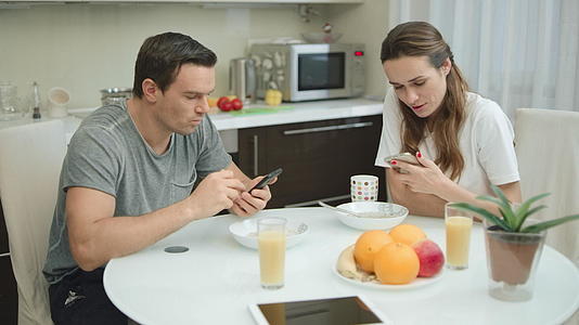 健康早餐期间一对夫妇在健康早餐期间寻找手机的快乐视频的预览图