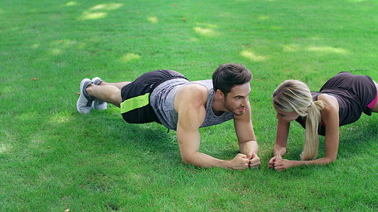 在户外健身训练中快乐的男女站在绿草木板上视频的预览图