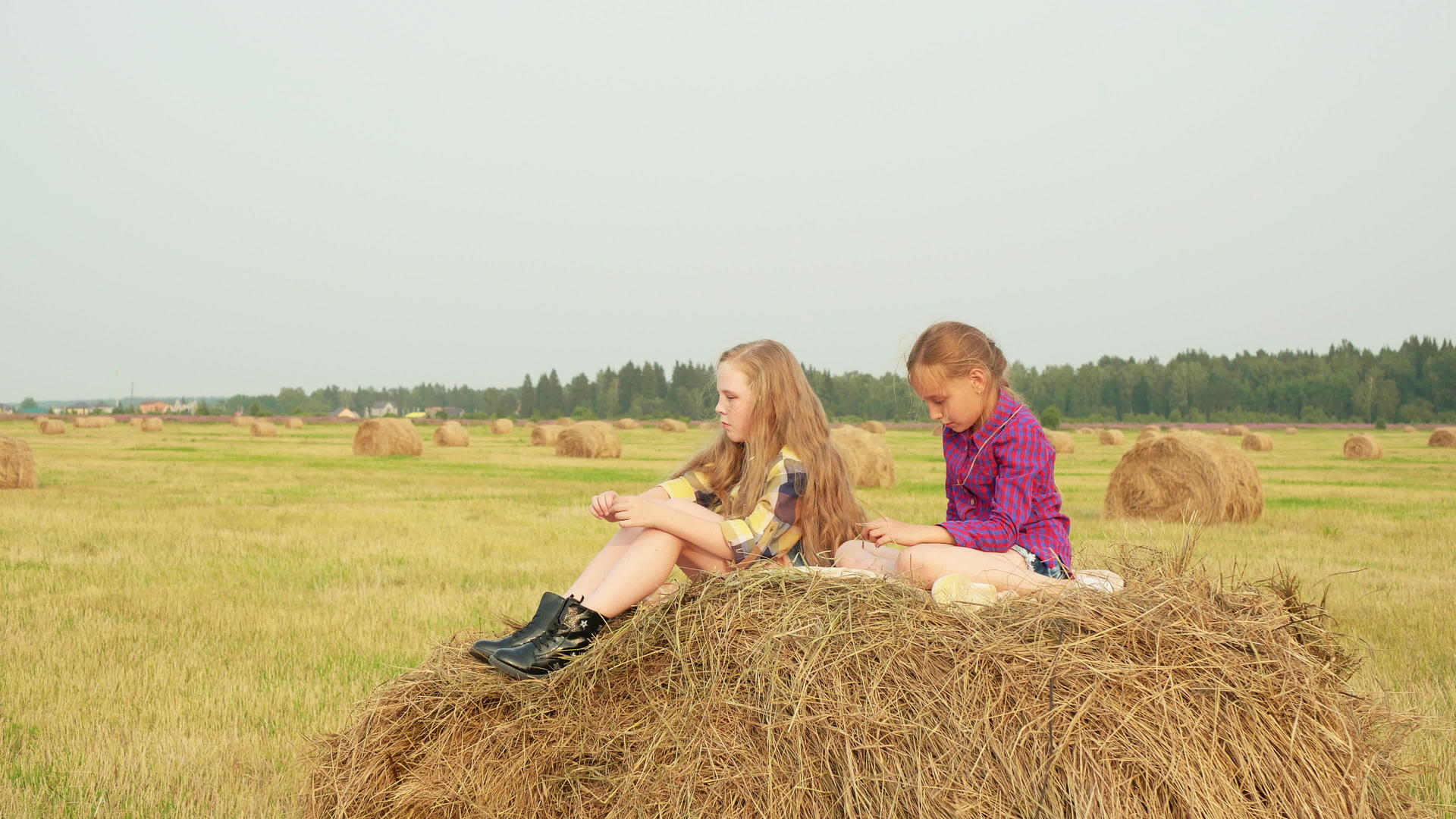 两个可爱的女孩穿着格斗衬衫坐在干草堆上视频的预览图