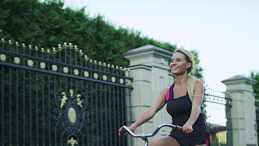 快乐的女人骑自行车在公园里挥手视频的预览图