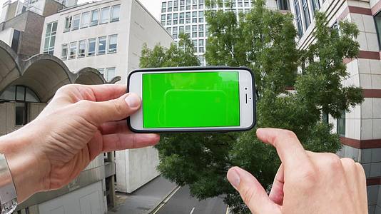 手持绿幕手机走在街上视频的预览图