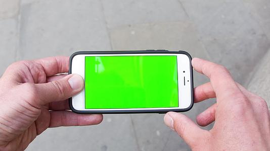手持绿幕手机走在街上视频的预览图