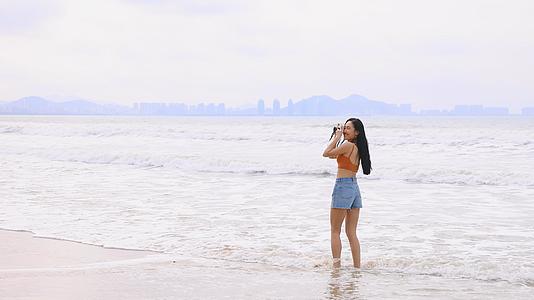 海边使用相机拍摄美好景象的美女视频的预览图