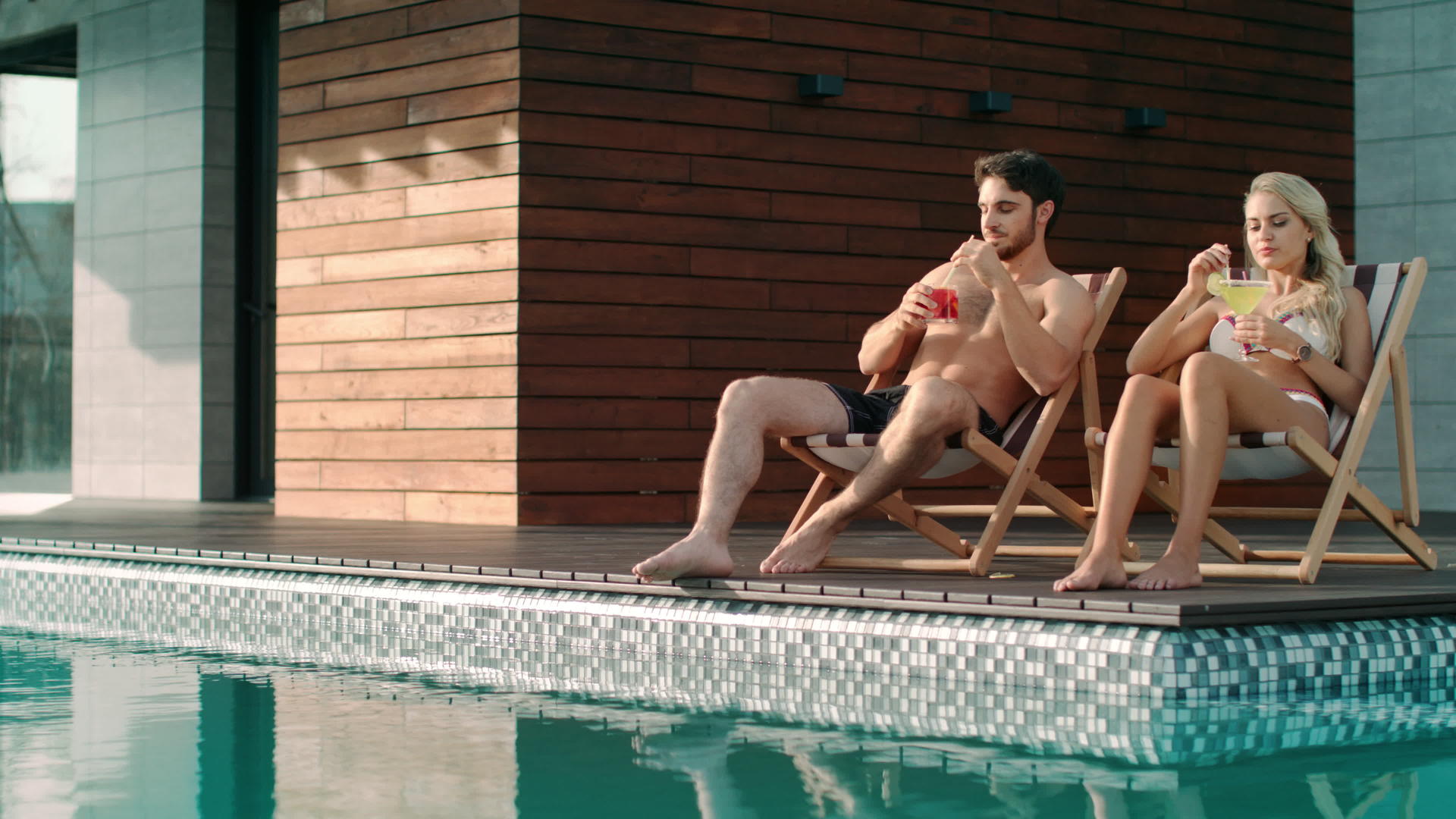在豪华家庭游泳池附近的太阳能椅子上放松视频的预览图