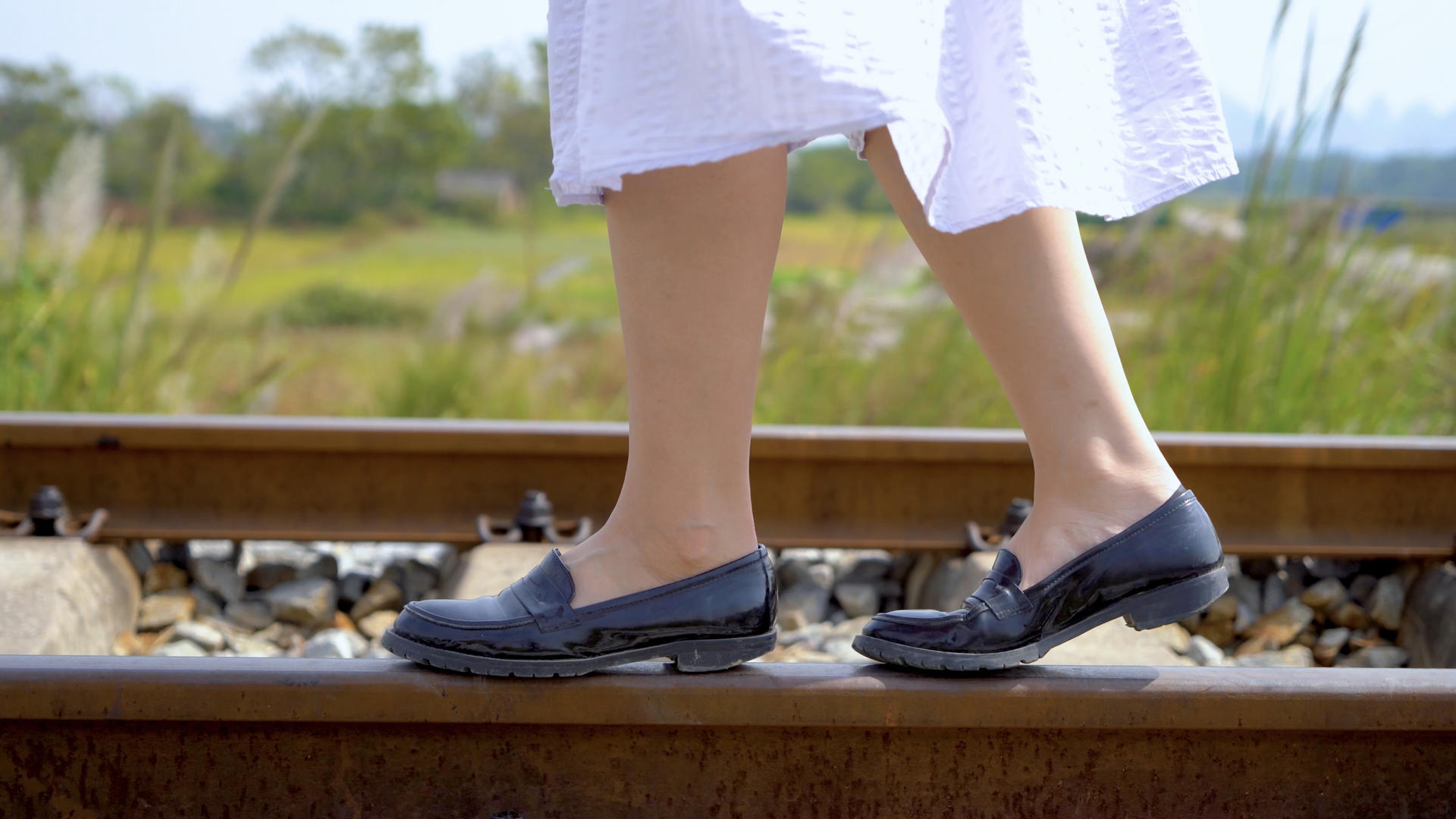 穿着裙子漫步在铁轨上的女孩脚步特写视频的预览图