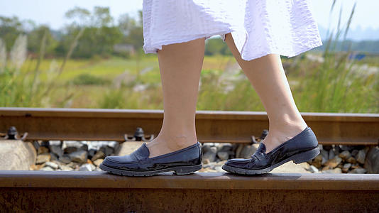 穿着裙子漫步在铁轨上的女孩脚步特写