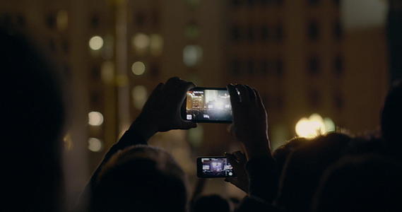 从手背看在狂欢派对上轻轻举起智能手机视频的预览图