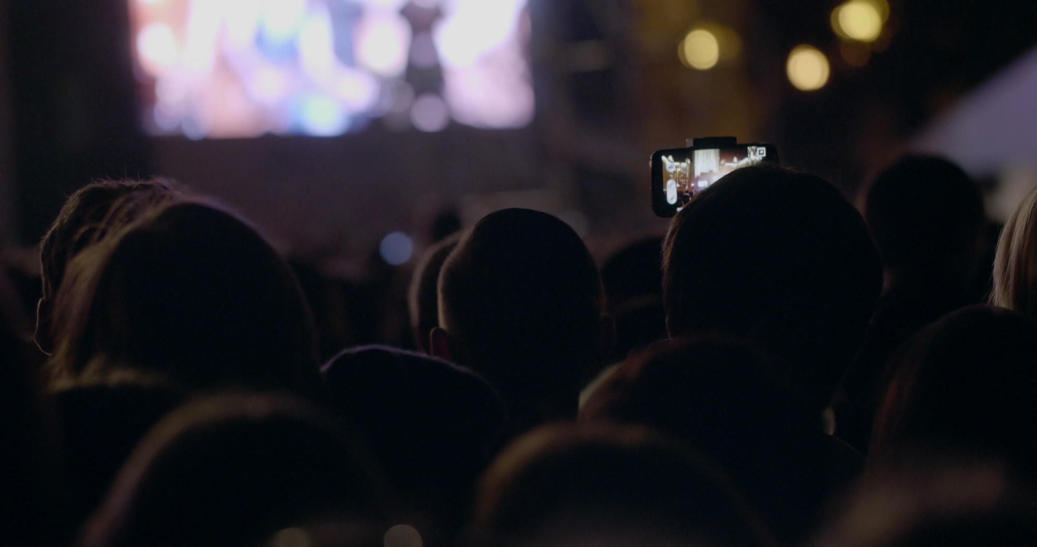 举起相机在有灯光的狂欢派对的人中间展示数字视频的预览图