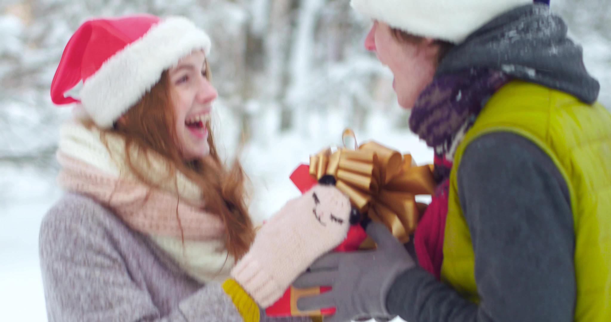 快乐的年轻夫妇在冬天的雪地里交换圣诞礼物视频的预览图