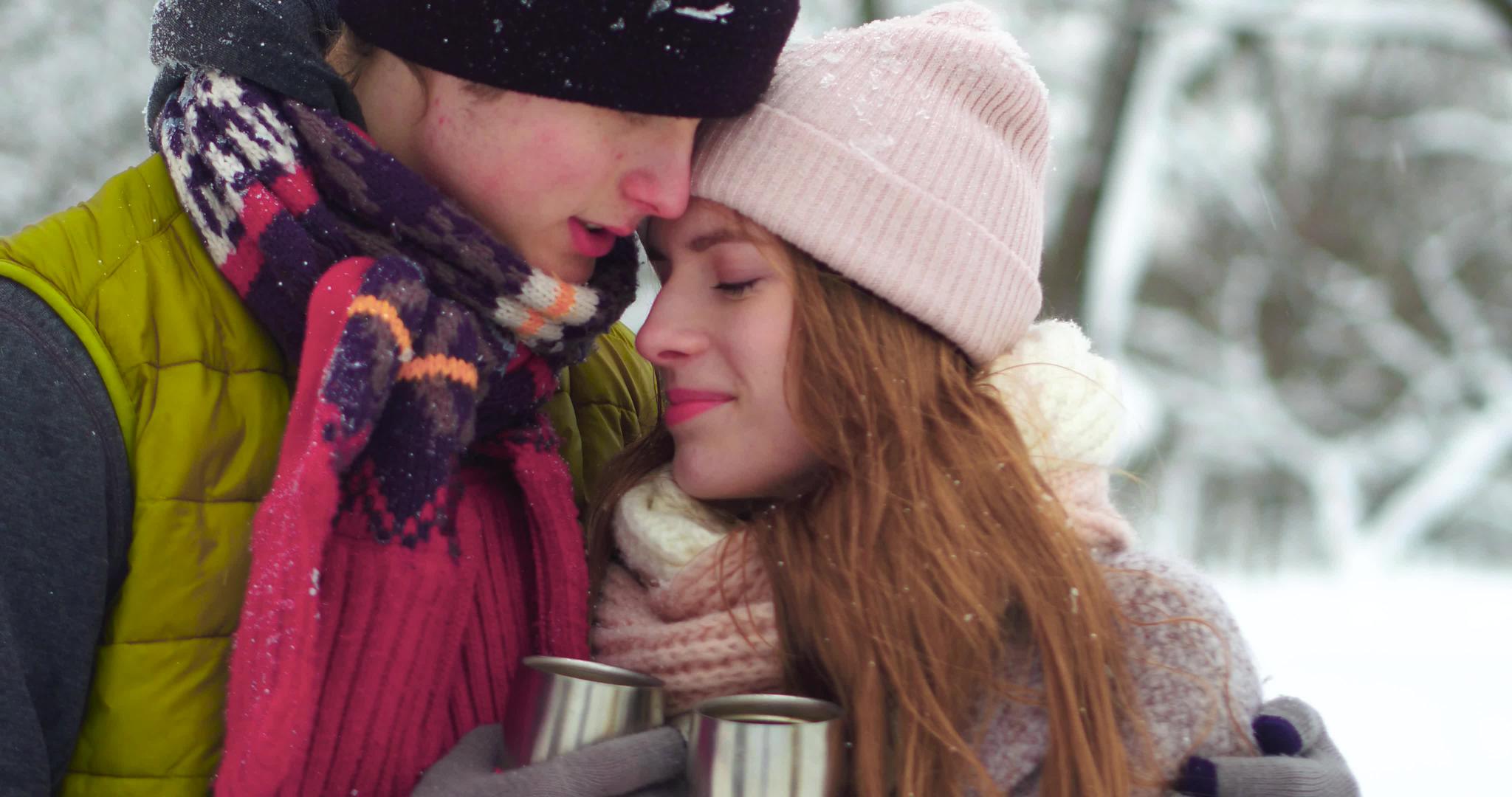 快乐的年轻夫妇在冬季雪地公园拥抱在一起视频的预览图