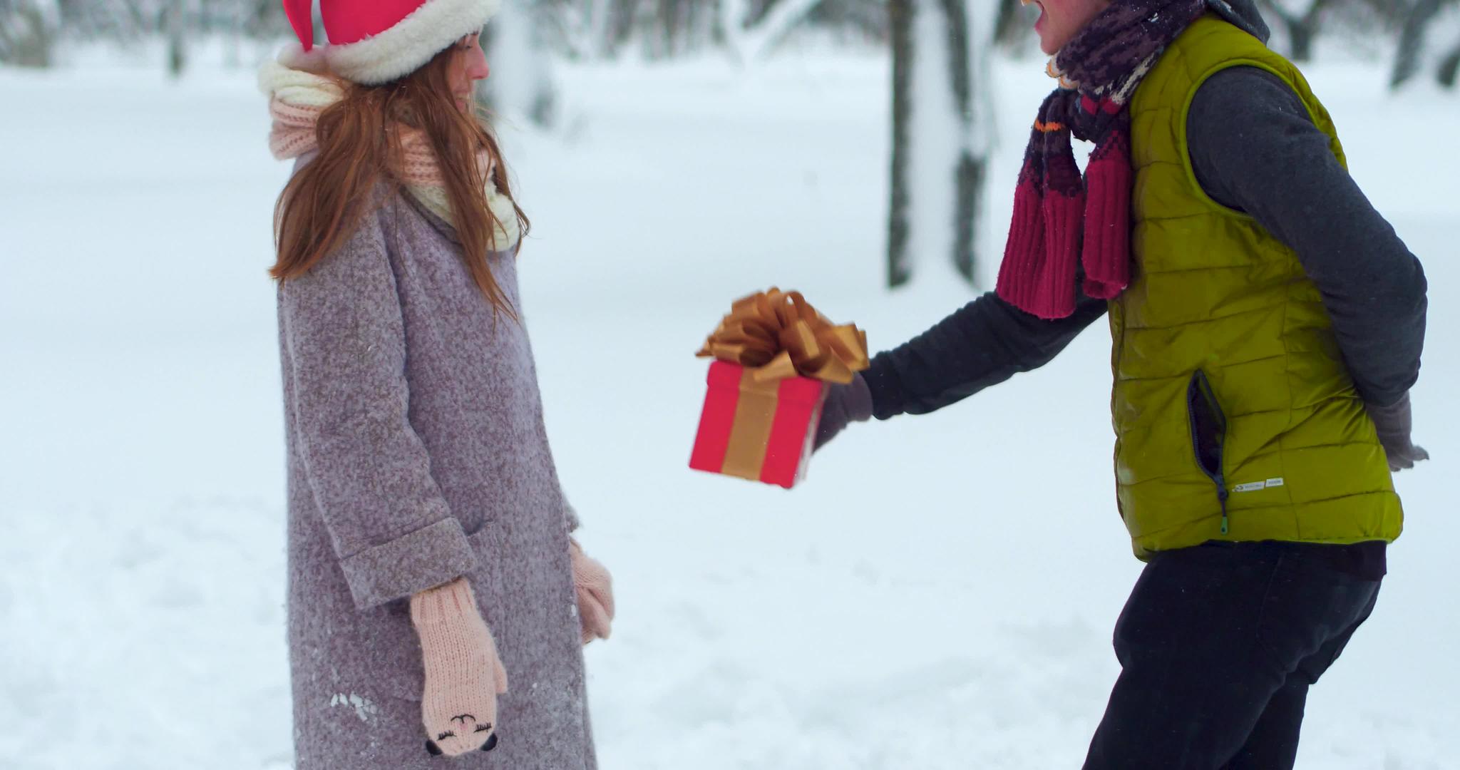 快乐的年轻夫妇在圣诞雪地里交换礼物视频的预览图