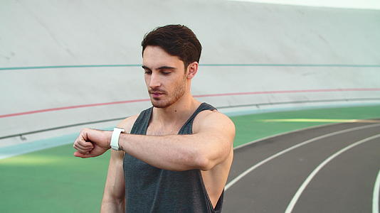 在跑道上使用智能手表的运动员肖像视频的预览图