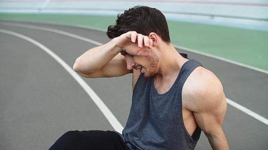 疲惫的男人在跑道上锻炼后休息视频的预览图