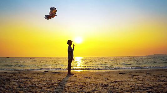 男孩在空荡荡的海滩上玩帽子风筝视频的预览图