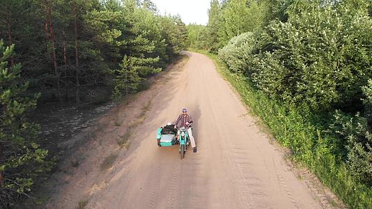 骑摩托车的男人和女孩在未铺好的道路上高角度搭车视频的预览图