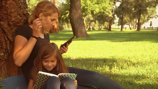母亲和女儿坐在树旁和女儿坐在一起视频的预览图