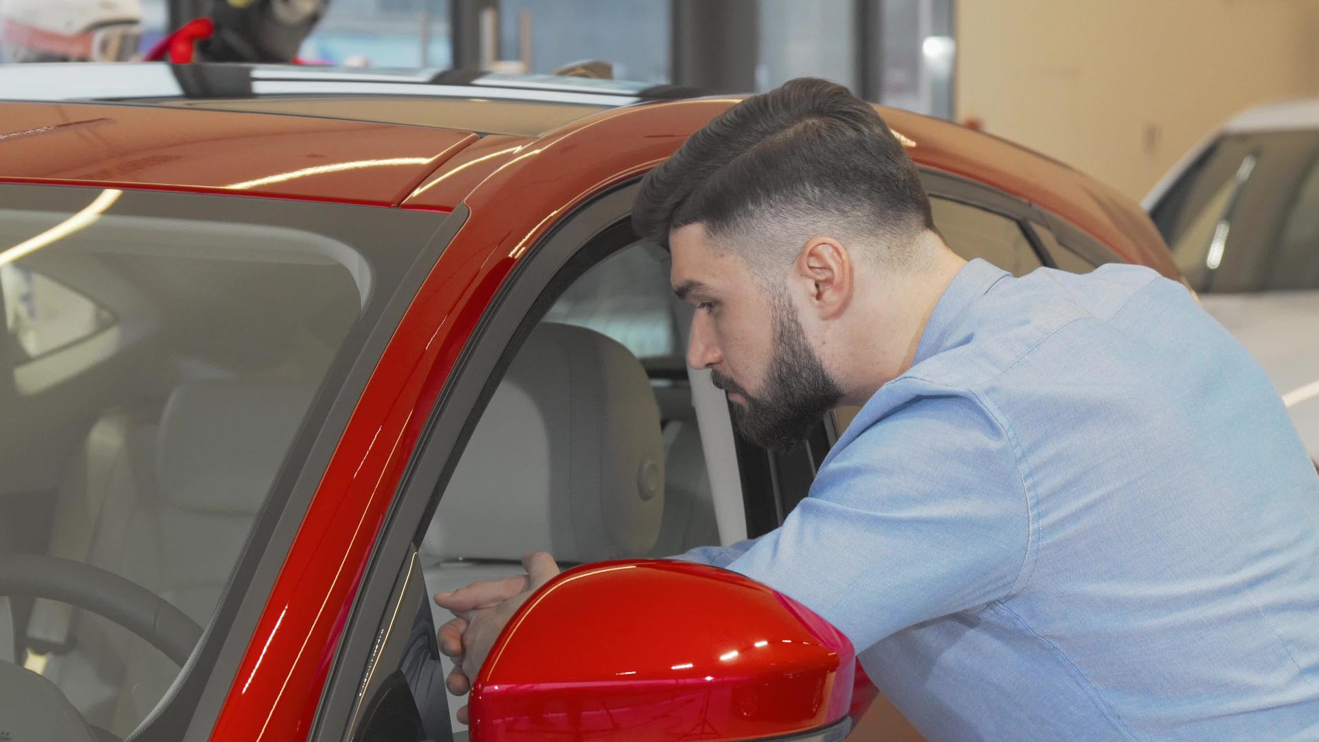 在检查出售的新车时男性顾客微笑着对着相机微笑视频的预览图