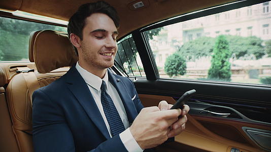 微笑的商人在商用车上用智能手机打字视频的预览图