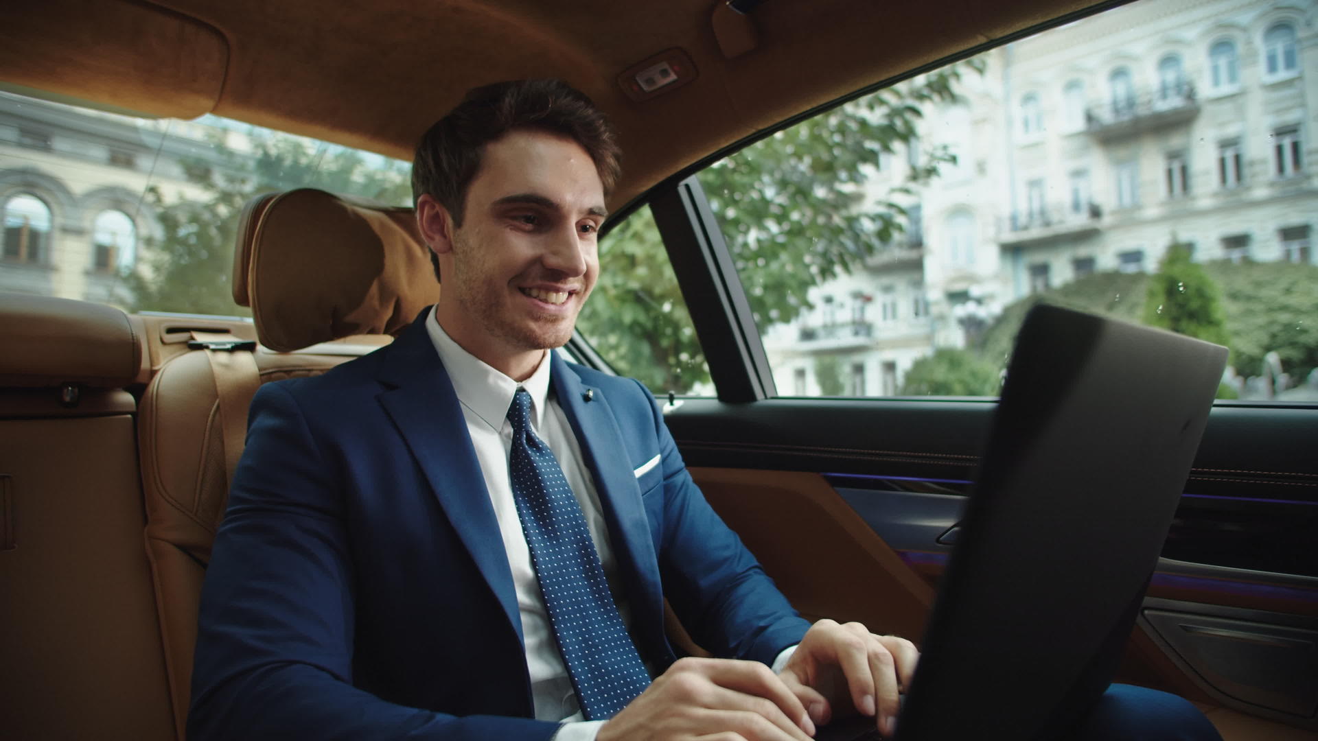 男人在豪华车上打开笔记本电脑庆祝成功视频的预览图