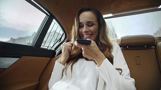 微笑的商业女性在现代汽车的智能手机上发送语音信息视频的预览图