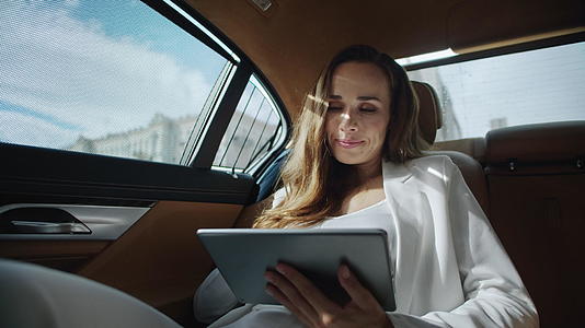 微笑着在商用车里用数字平板电脑工作的女商人肖像视频的预览图
