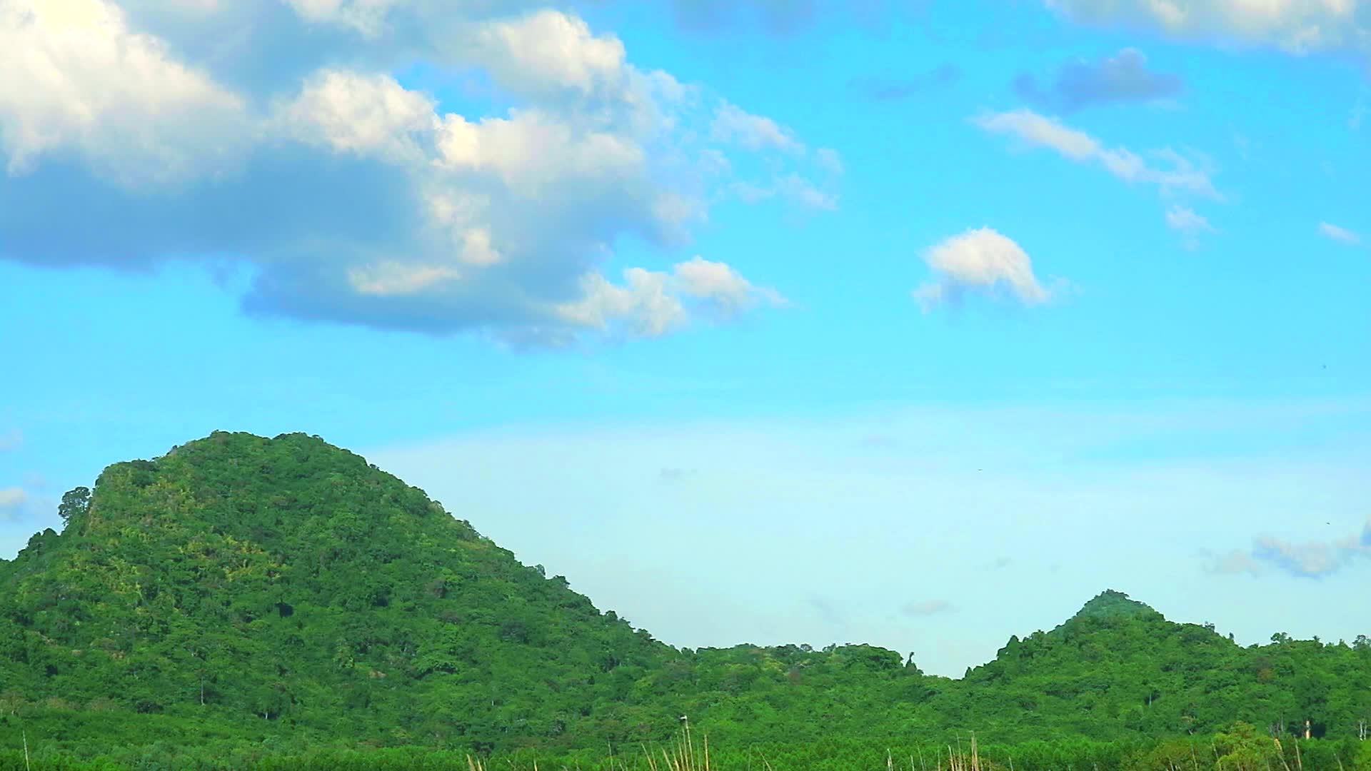 白云在山顶和蓝天中漂浮视频的预览图