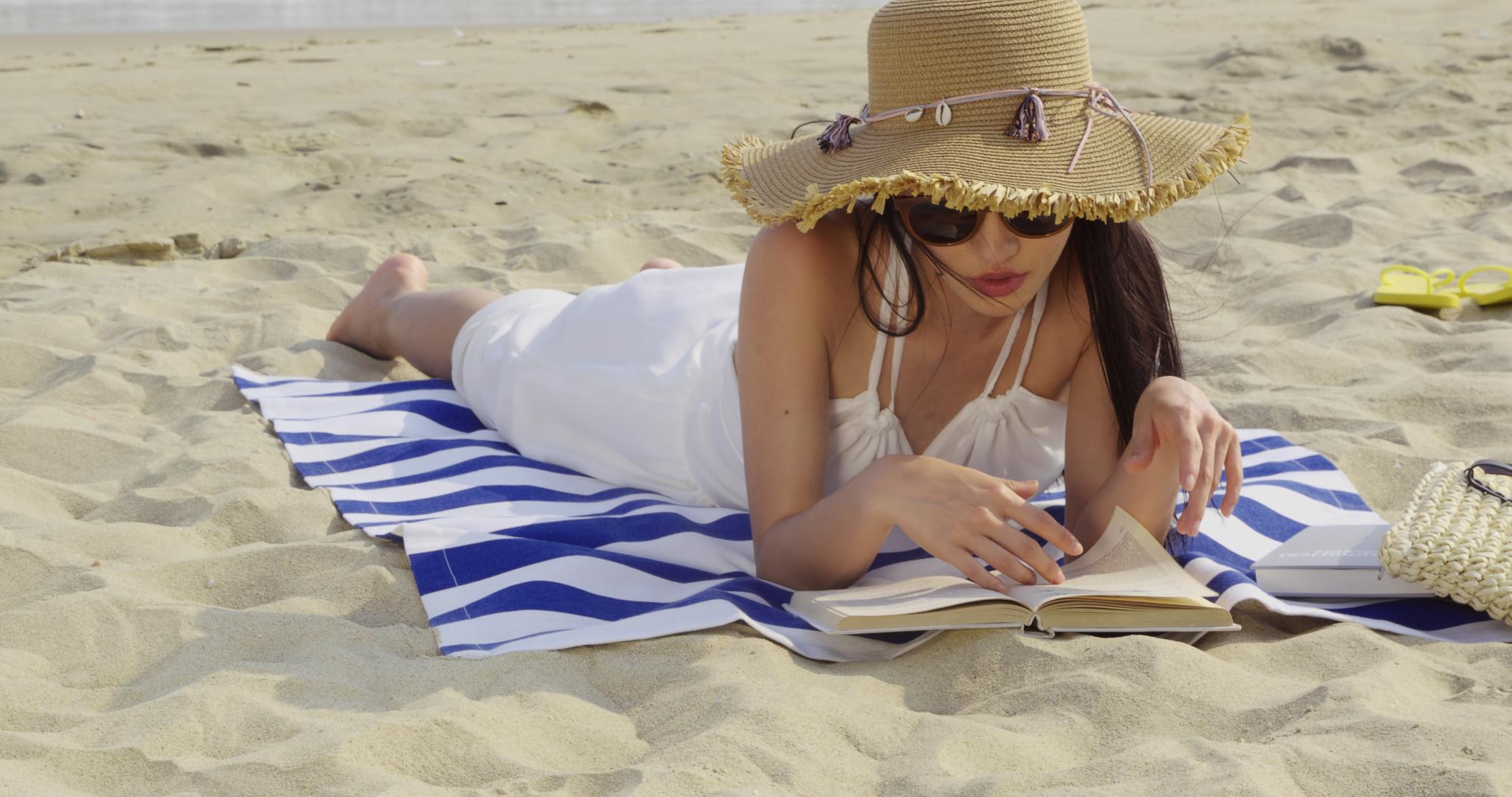 8K戴墨镜女性沙滩上看书视频的预览图