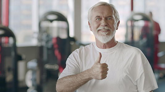 微笑的老人在健身俱乐部做了一个拇指手势视频的预览图