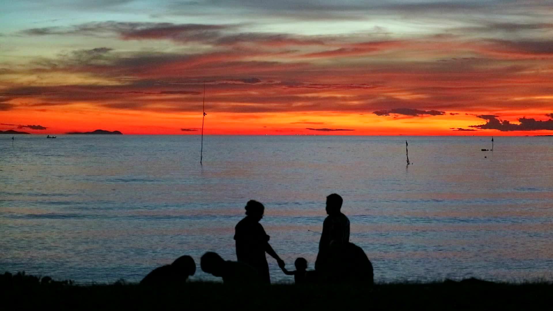 一家人在海边拍日落照在海滩上散步视频的预览图