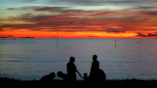 一家人在海边拍日落照在海滩上散步视频的预览图