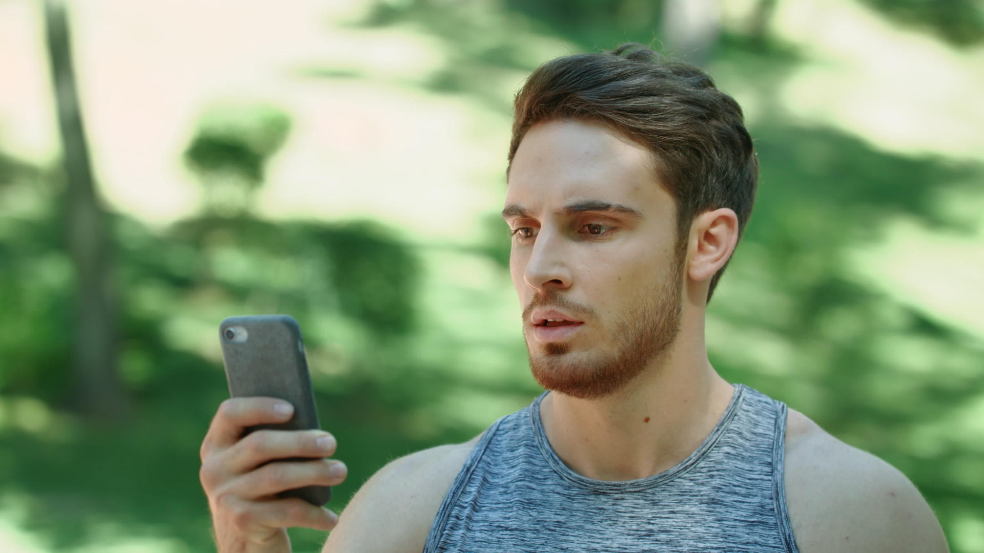 体育男子看着手机在公园里跑步视频的预览图