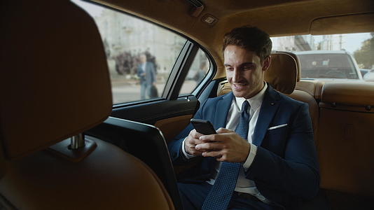 职业男性在车里快乐地使用手机视频的预览图