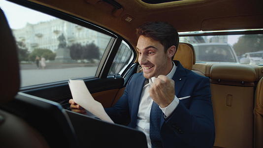 在汽车中看到优秀数据的职业男性欣喜若狂视频的预览图