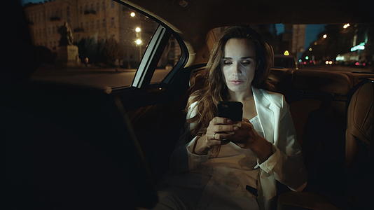 深思熟虑的职业女性在黑暗的汽车中使用手机发送信息视频的预览图