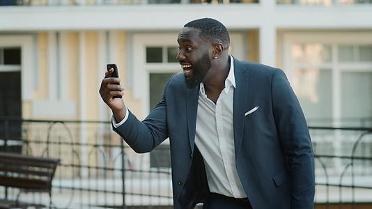 黑人职业男性在街上的视频电话里欢呼听到好消息视频的预览图
