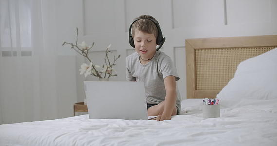 沉迷于网络的小男孩正在使用笔记本电脑进行交流和游戏视频的预览图