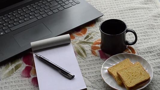 早餐咖啡和笔记本电脑黑笔和白纸笔记本电脑视频的预览图