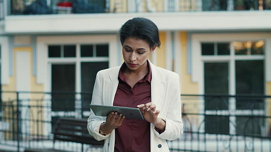 白领女性在外面滚动平板电脑阅读信息视频的预览图