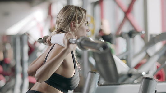 强壮的女性在健身中心用巴铃做蹲下运动视频的预览图