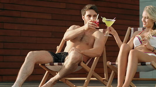 在豪华游泳池附近的太阳椅上喝鸡尾酒视频的预览图