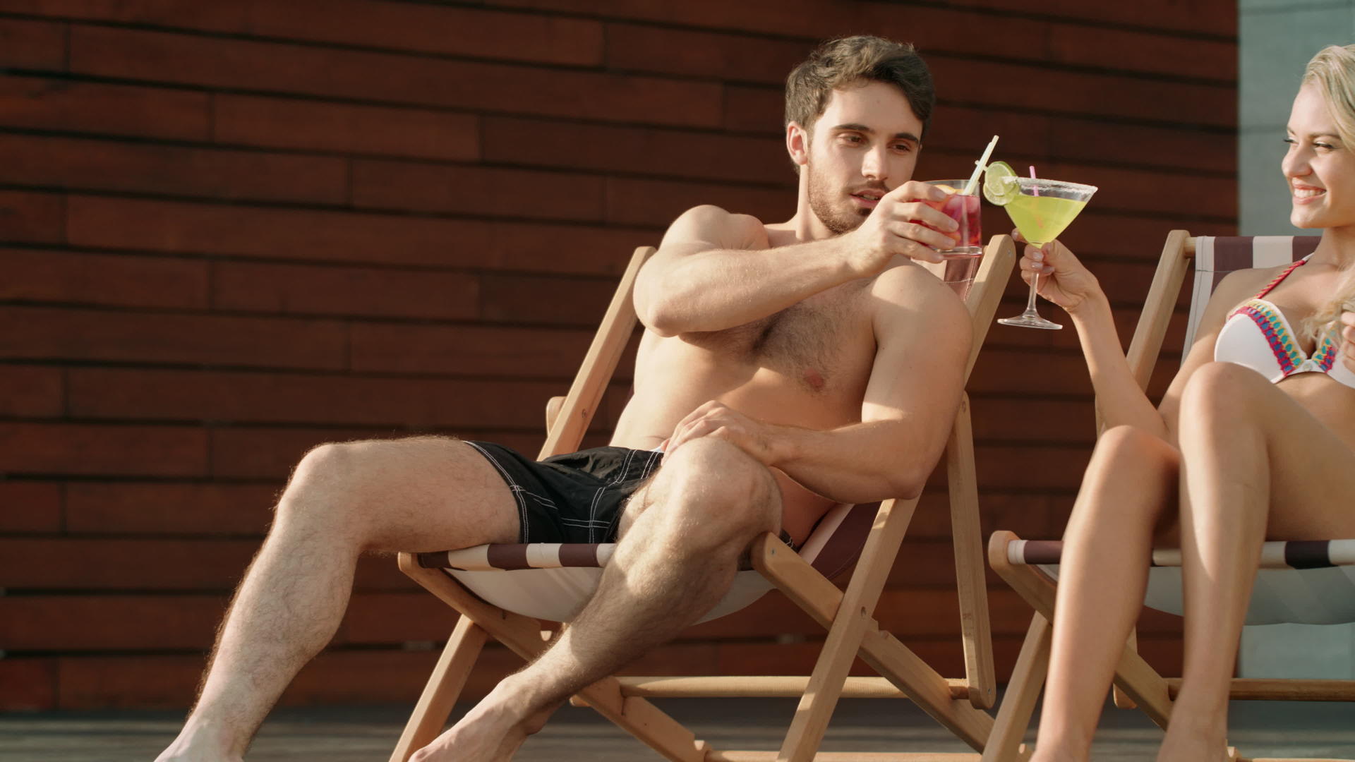 夏天情侣们在太阳椅上喝鸡尾酒视频的预览图