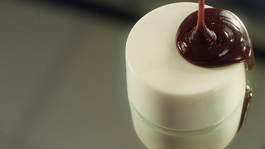 专业厨房使用热巧克力加热巧克力美味的蛋糕倒在白玻璃里视频的预览图
