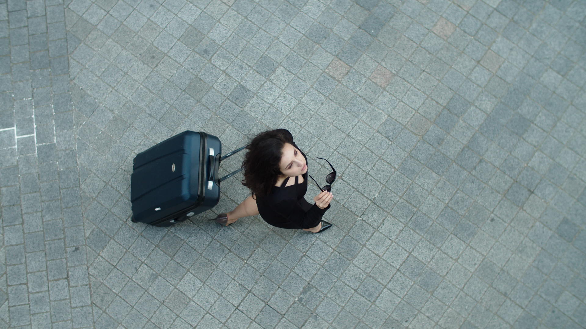 一个优雅的女人拿着她的手提箱走在户外摘下太阳镜视频的预览图