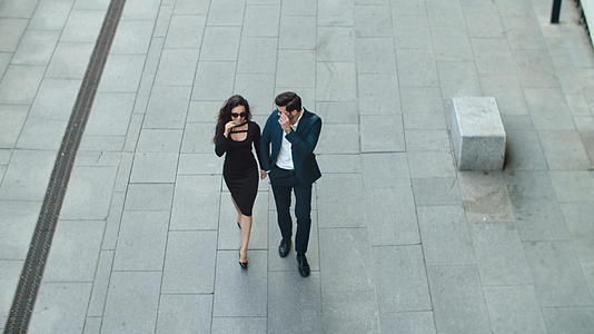 时尚的商业情侣戴着太阳镜走在人行道上视频的预览图