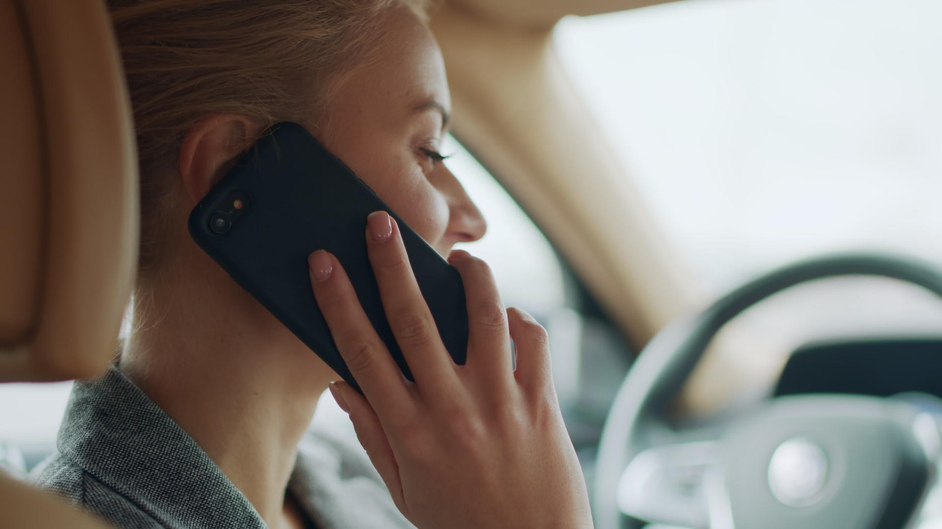 女性在汽车驾驶座上愉快地谈到电话侧面的特写视频的预览图