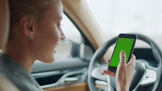 女性在汽车驾驶座上愉快地使用手机打字有绿色屏幕视频的预览图